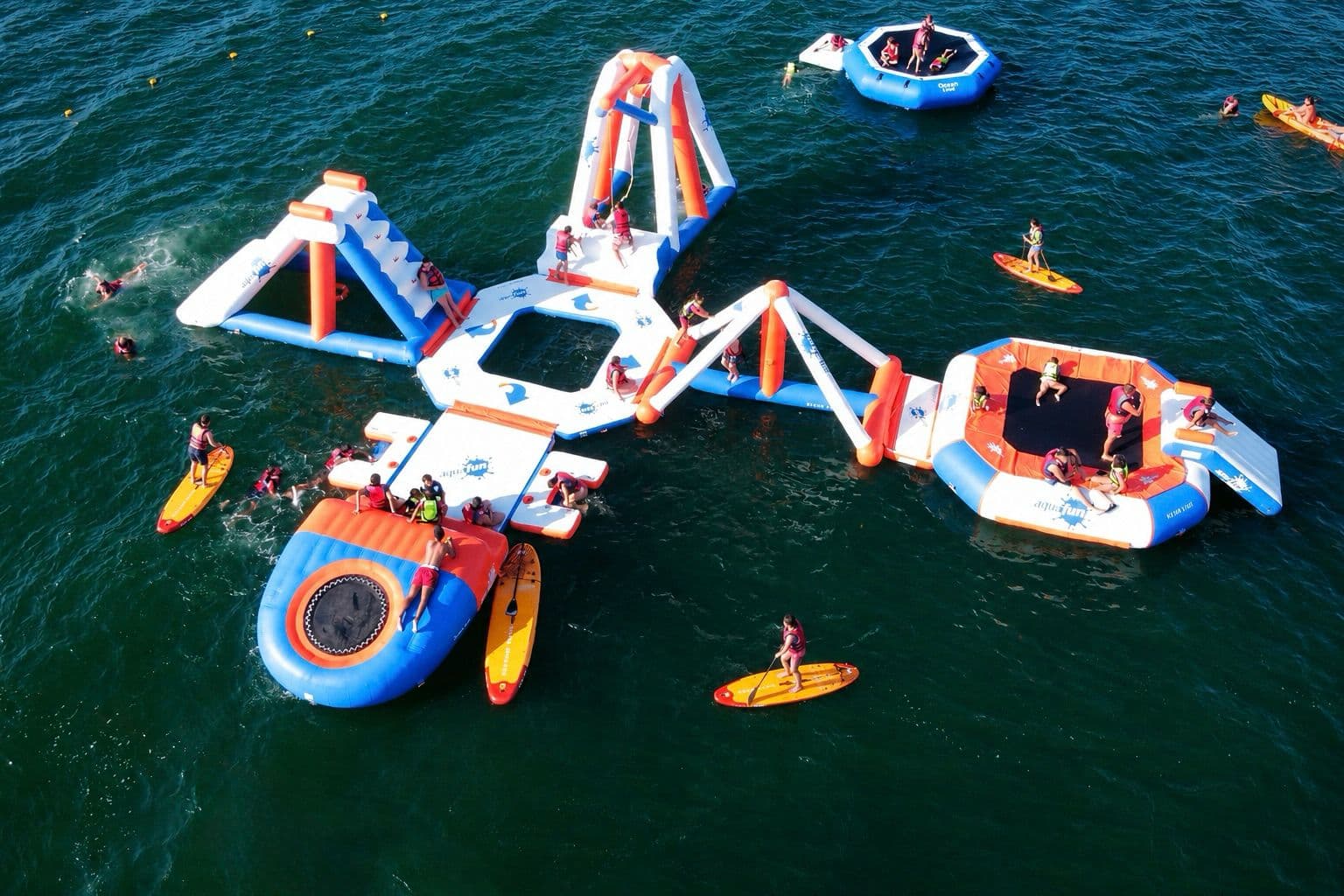 Vista aérea de Ozean Park con parque acuático flotante, paddle surf y usuarios en el mar